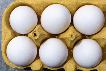 Fresh white eggs in a yellow carton ready for cooking or baking on a kitchen countertop