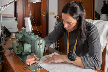 Woman sewing fabric using vintage sewing machine at home