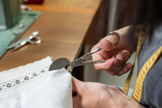 Hands using tailoring scissors cutting white fabric
