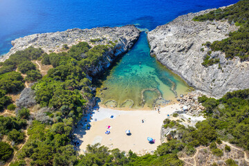 Aerial view of the V shaped Glossa beach in Messinia, Peloponnese, Greece, with turquoise sea surounded by rocks and cliffs