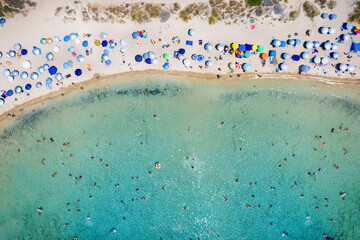 Aerial overhead view of a crowded beach with turquoise sea as seen in Messinia, Greece, during summer time