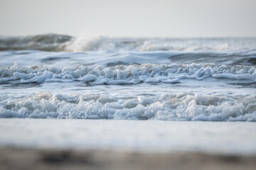 Waves crash on a sandy beach at sunset, creating a tranquil scene for evening relaxation and reflection