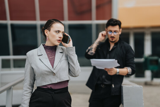 Business professionals carrying out a phone conversation and reviewing documents outside an office building.