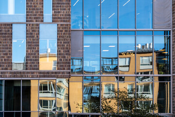 Urban architecture expressed via reflection on a glass facade where minimal symmetry, soft light and vivid color enhance each modern detail