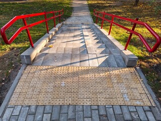 Pedestrian walkway in the autumn park with red railing.