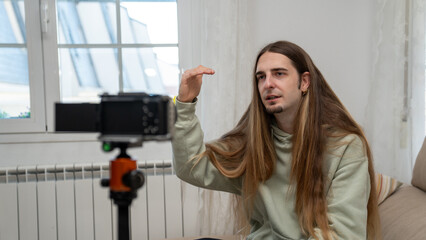Man vlogging, creating video content for social media, recording with camera on tripod, influencer livestreaming