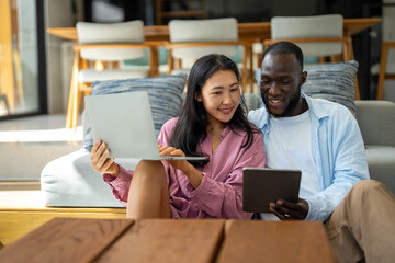 Happy multiethnic couple with laptop making plan for investments, savings and budget for bills