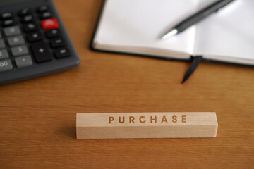 purchase. financial concepts. word written on a wooden block with a calculator, notebook, and pen
