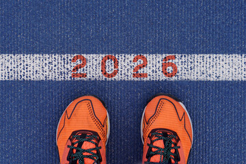 2026 new beginning concept. feet with orange sneakers at the starting line of a running track