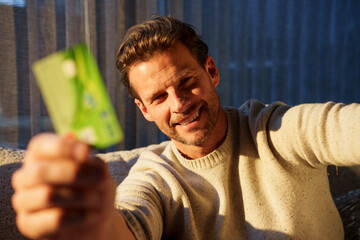 Smiling person holding credit card indoors showing affection and trust