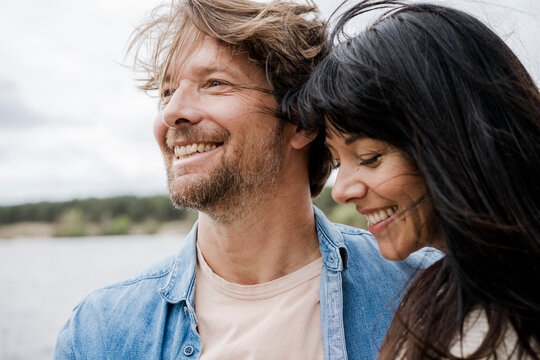 Smiling couple enjoying a windy day together outdoors by a lake