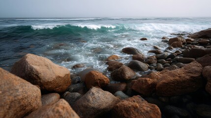 A rocky coastline with powerful waves crashing against boulders under an overcast sky