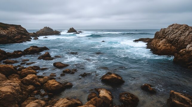 Rugged rocky coastline with churning blue ocean waves under a cloudy dramatic sky - Powered by Adobe