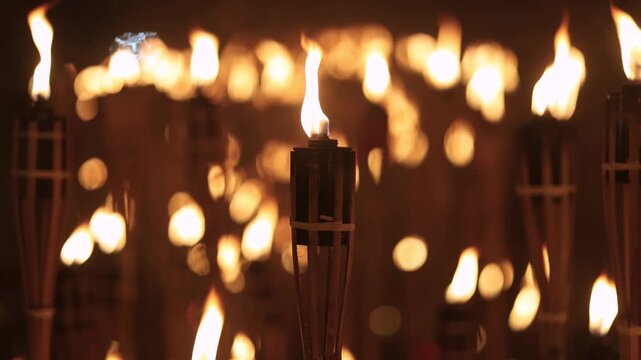A captivating night scene of lit bamboo torches Warmflickering flames create a dramatic glow against the dark with soft bokeh lightsancient ritual cultural celebration spirit in a timeless spectacle