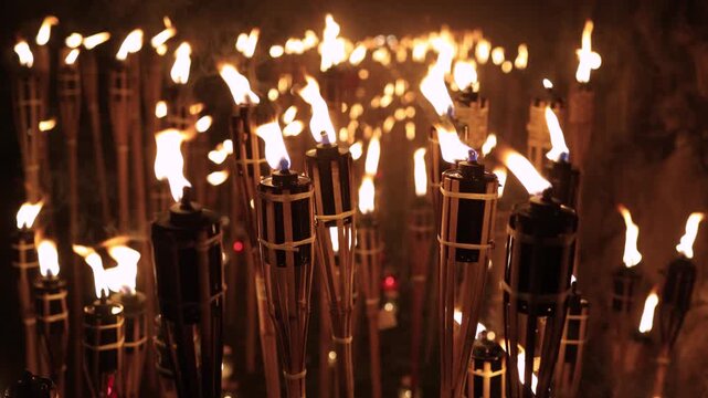 A captivating night scene of lit bamboo torches Warmflickering flames create a dramatic glow against the dark with soft bokeh lightsancient ritual cultural celebration spirit in a timeless spectacle