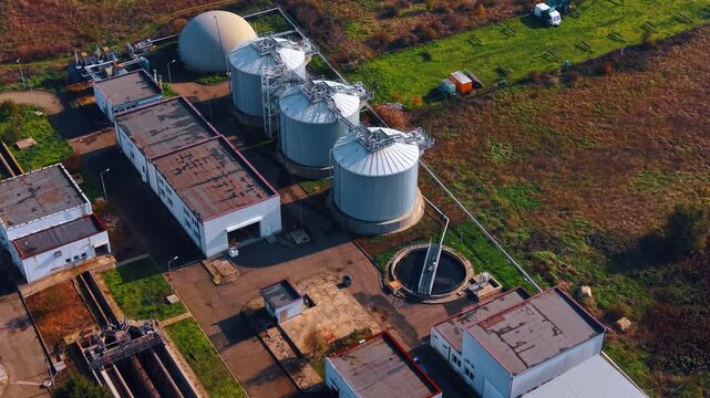Metal tanks and low-rise buildings at the territory of the plant. Aerial view on the large reservoirs for sewage water. Eco-friendly lifestyle.