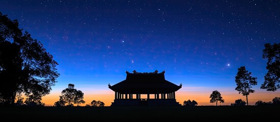 Obraz premium Silhouette of a Traditional Asian Building Under a Starry Night Sky.