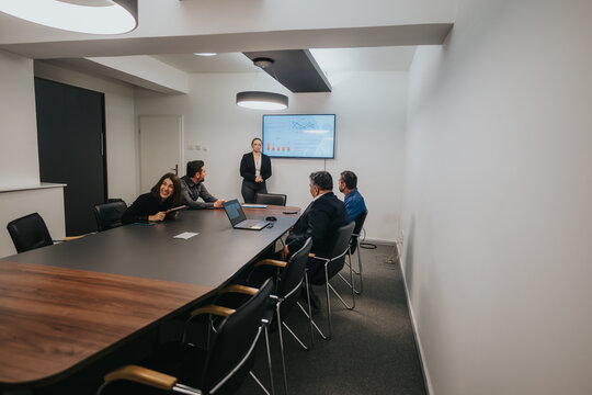 A group of business professionals meeting in a well-lit modern office, analyzing data on a screen and discussing strategies.