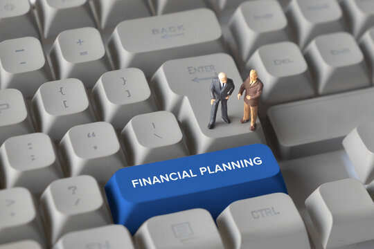 Miniature Business Figures Standing on Keyboard Button with Text Financial Planning. Representing budgeting, investment decisions, revenue forecasting, and corporate financial strategy.