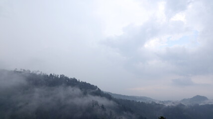 Foggy mountain range covered in dense clouds creating a mysterious and atmospheric landscape in the wilderness, showcasing nature's power and tranquility.