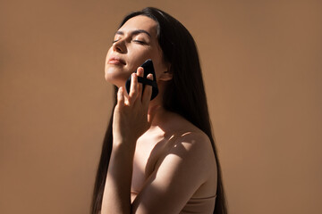 Asian woman with long hair gently using a facial cusion care on her cheek, illuminated by soft natural light, creating a serene and calming beauty routine atmosphere