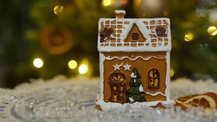 Christmas decoration. Cute gingerbread house, Christmas tree on background. Cozy home decor.