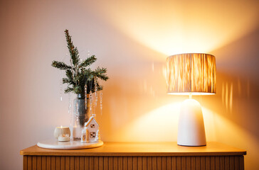 Cozy interior scene featuring a decorative lamp, small evergreen plant, and candle on a wooden table, creating a warm and inviting atmosphere for home decor inspiration