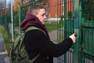 Young student with backpack unlocking security gate