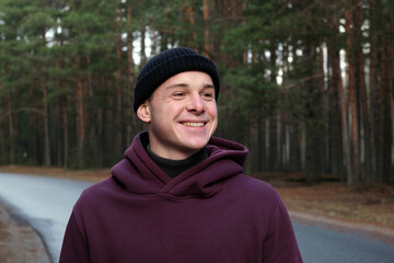 Young man smiling walking on road in forest