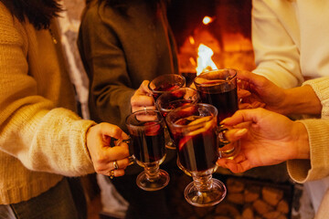 Close-up of the women saying a toast and clinking glasses with mulled wine