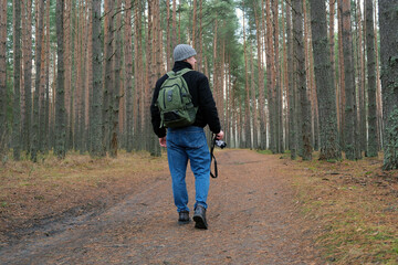 Man photographer walking on a forest trail with backpack