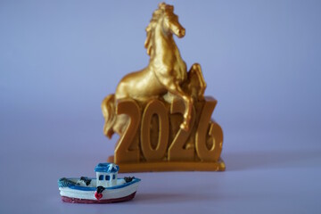 A toy boat on the background of a statuette of a horse.