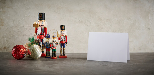 A festive Christmas scene featuring classic wooden nutcracker figurines, decorative ornaments, and a blank greeting card on a textured background, perfect for holiday promotions.
