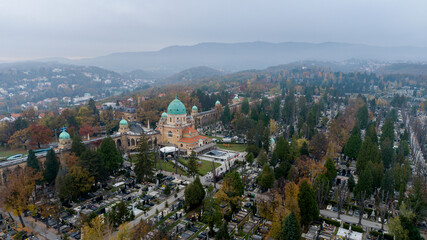 Aerial view of Mirogoj Cemetery's neo-Byzantine domes rise serenely above the autumnal trees, a place of peace and remembrance amidst a misty landscape, Zagreb, Croatia.