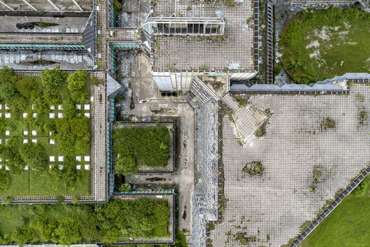 Aerial view of overgrown rooftops with patches of vibrant green vegetation contrasting against weathered concrete, Zagreb, Croatia.
