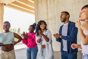 Diverse young adults clapping and smiling during urban hangout