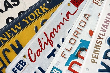 Old US car license plates with various state names close up. Concept of driving in United States. Reaching a car registration