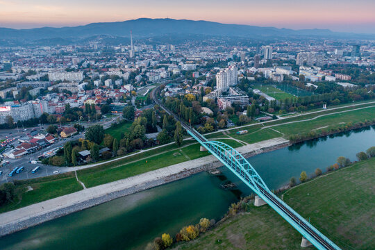 Aerial view of the Sava river reflecting the sky with a blue bridge spanning its waters, the city sprawling beyond, Zagreb, Croatia.
