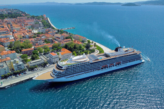 Zadar, Croatia - 18 November 2025: Aerial view of a majestic cruise ship docked near the old town, where terracotta roofs meet the azure Adriatic Sea.