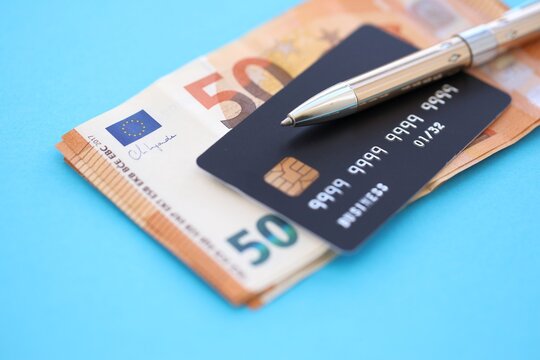 Credit card and pen with euro currency money bills banknotes on light blue background. Business, financial operations and accounting in European Union