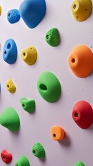 Diagonal array of bright climbing holds on a bright indoor bouldering wall in a gym showcasing kids sports activity