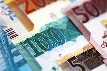 Qatari riyal money bills banknotes lies in big pile on table close up. Concept of finances and business in Qatar