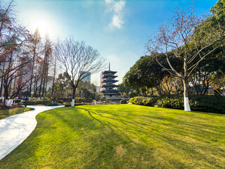 Obraz premium Tranquil Park Landscape Featuring a Pagoda Amidst Lush Greenery and Clear Blue Skies