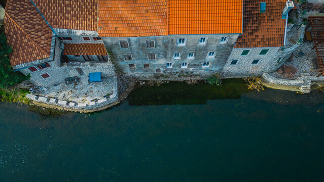 Aerial view of terracotta rooftops meet the dark, reflective waters, ancient stone walls standing firm against the flow of time, Trebinje, Republika Srpska, Bosnia and Herzegovina.