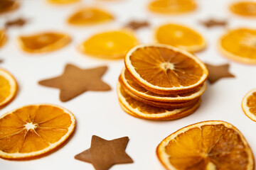 dried dehydrated orange slices, homemade handmade star shaped gingerbread cookies and red ribbon bow on white paper background. Christmas vibe texture