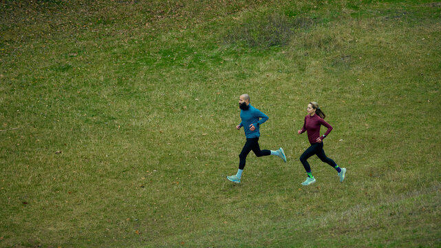 Runners keeping steady pace across open green hillside. Concept of light cardio, daily training habit, outdoor fitness practice, calm movement, simple healthy routine. - Powered by Adobe