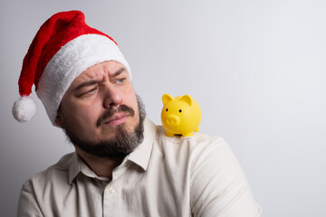 Man in santa hat looking at piggy bank on shoulder