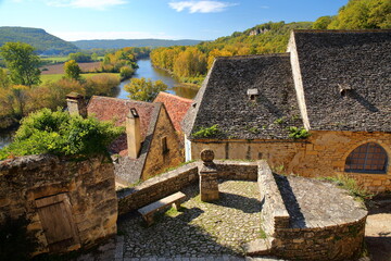 Traditional medieval houses with sloping slate roofs in the village Beynac et Cazenac, Dordogne, France, built on a magnificent cliff and overlooking the river Dordogne, with autumn colors