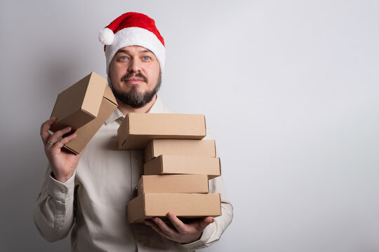 Happy man in santa hat holding stack of delivery boxes