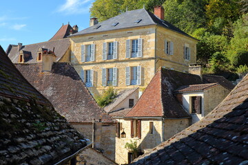 Traditional medieval houses with sloping slate roofs in the village Beynac et Cazenac, Dordogne, France, blend into a magnificent cliff